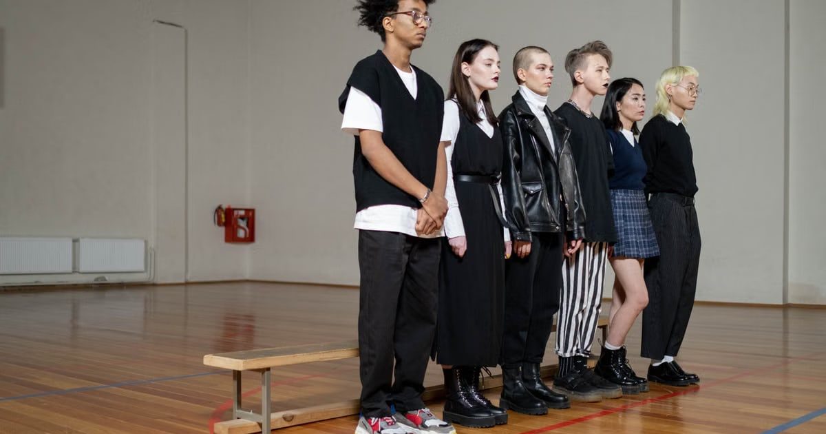 Diverse group of stylish teenagers standing in a gym, showcasing modern fashion trends.