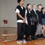 Diverse group of stylish teenagers standing in a gym, showcasing modern fashion trends.