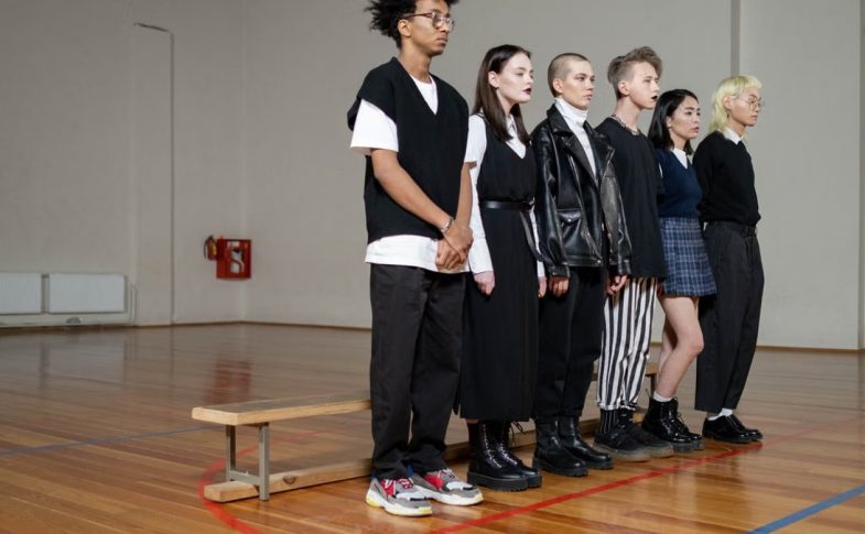 Diverse group of stylish teenagers standing in a gym, showcasing modern fashion trends.