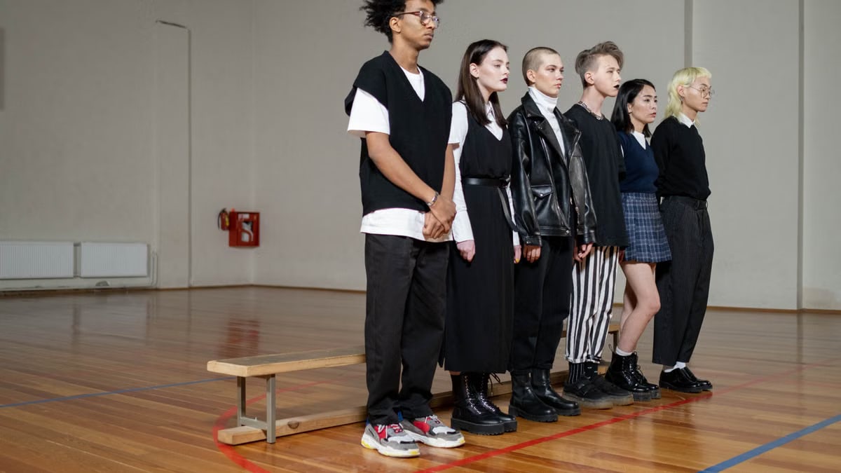 Diverse group of stylish teenagers standing in a gym, showcasing modern fashion trends.