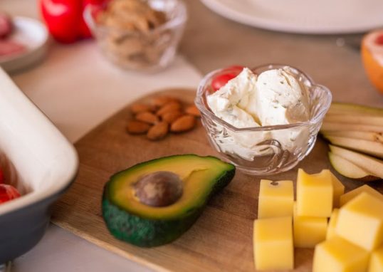 A vibrant platter of cheese, fruits, and vegetables on a wooden board, perfect for gatherings.