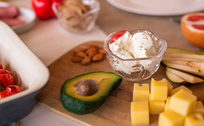 A vibrant platter of cheese, fruits, and vegetables on a wooden board, perfect for gatherings.